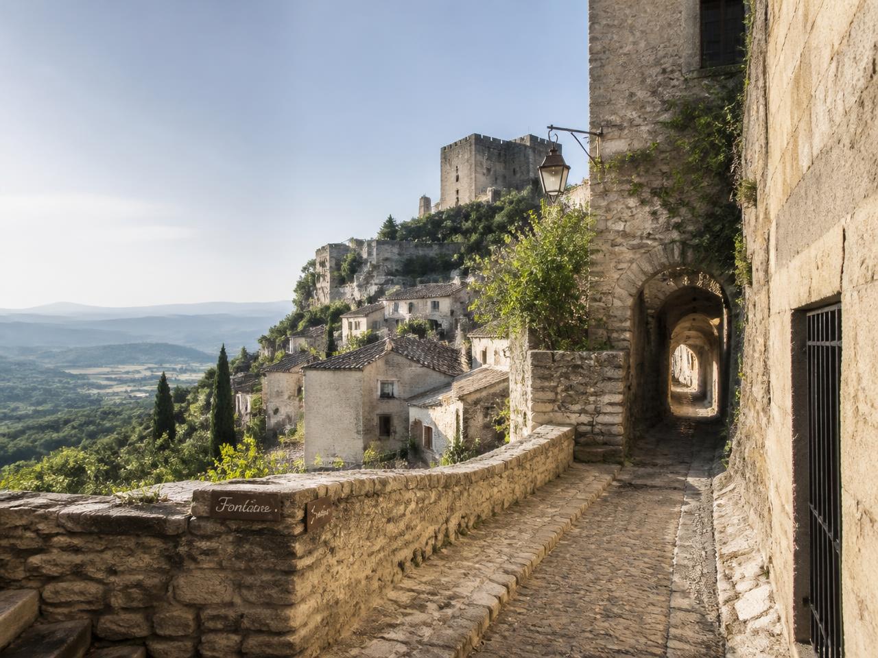 Ruelle pavée et passage voûté en pierre du village perché de Crestet, avec vue sur la vallée de l'Ouvèze