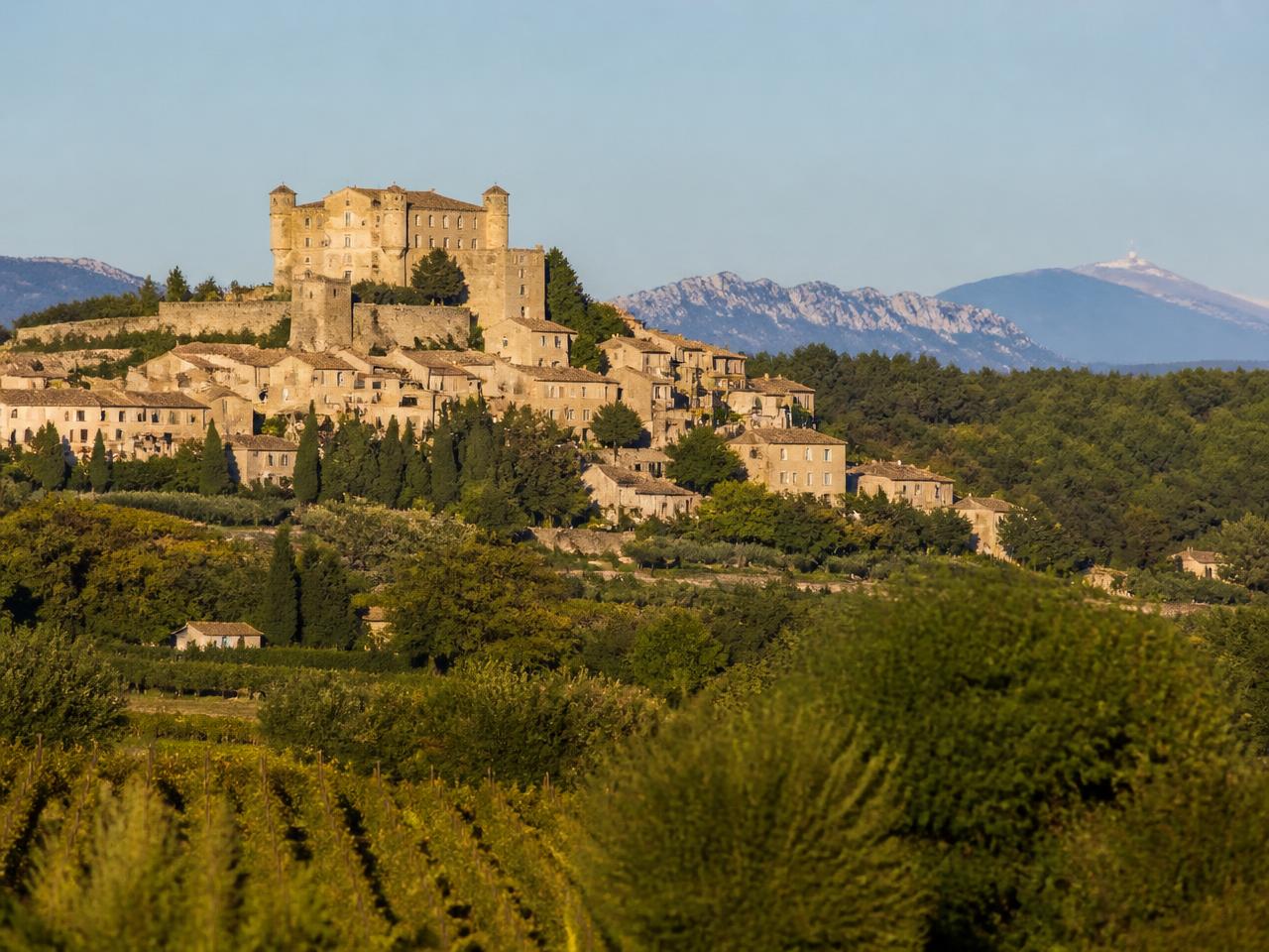 Le village perché du Barroux dominé par son château, entouré de vignes et d'oliviers face au Mont Ventoux